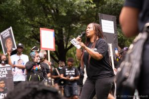Family members of Jamarion Robinson use a microphone to speak to protesters
