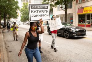 A protester marches through the streets holding up a 'Justice for Kathryn Johnston'