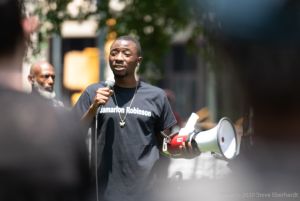 A protester uses a microphone to give a speech while holding a bullhorn