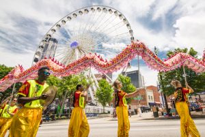 Festival Participants use sticks to walk a moving dragon through the parade