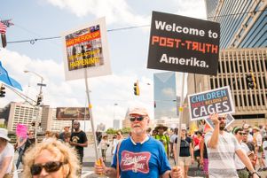 A protester holds up multiple signs calling for America to wake up