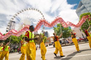 Festival Participants use sticks to walk a moving dragon through the parade