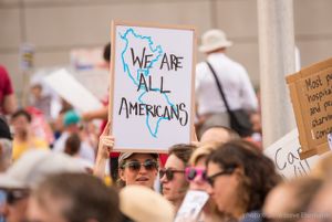 A protester holds up a sign reading 'We are all Americans'