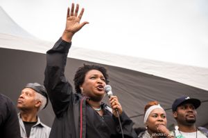 Stacey Abrams holds a hand in the air while giving a speech to protesters