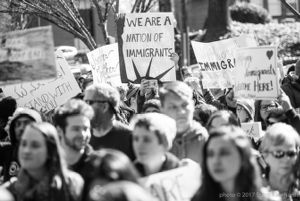 Protesters gather together holding signs to protest Trump's Immigration Policy