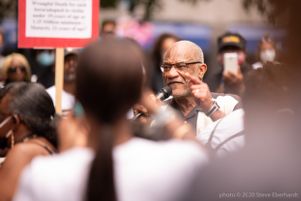 An older protester speaks to other protesters while pointing