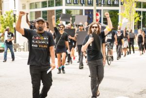 Protesters march through the streets with taped mouths and fists held in the air