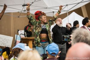 A member of Atlanta's Arrested Development holds her arms in the air after speaking