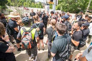 Protesters stop at a street corner and gather to listen to a speech being given