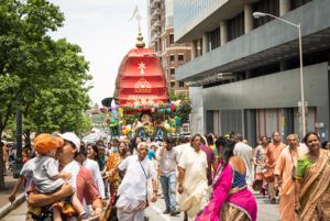 Festival Participants dance and hold onto a rope to help pull the cart through the streets