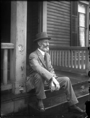 Elderly man sitting on a stoop, circa 1918.
