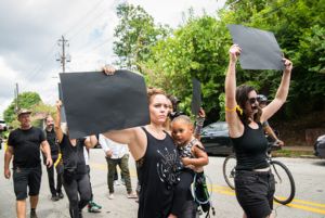 Protesters march through the streets holding blacked out signs