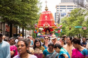 Participants walk in front of a large red ornate cart