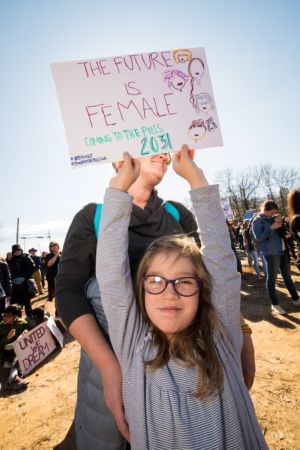 A young girl holds up a sign reading 'The Future is Female'