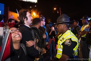 Protesters link arms as they stand off with Police Officers