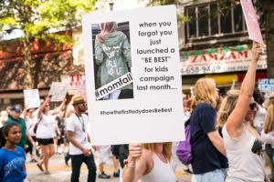 A protester holds up a sign critiquing the First Lady of the United States