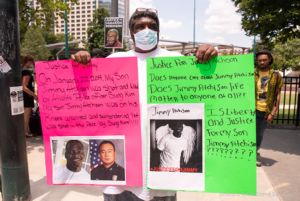 A protester holds up two signs calling for justice for his lost son