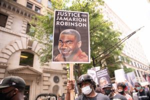 A protester holds up a sign reading 'Justice for Jamarion Robinson'