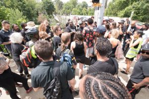 Protesters stop at a street corner and gather to listen to a speech being given