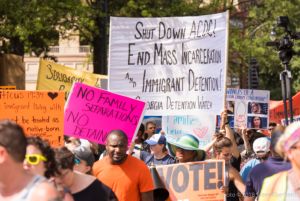 Protesters gather together holding up a multitude of signs as they protest
