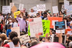 Reverand Raphael Warnock raises a arm in the air while he speaks to protesters