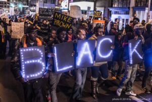 A crowd of protesters hold signs while marching down Peachtree Street
