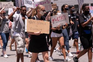 A protester carries a sign reading 'White Silence is Violence'