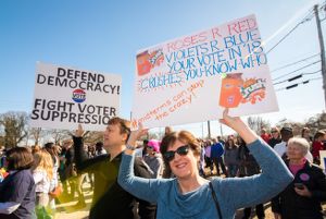 Protesters hold up signs calling people to vote and fight voter suprression