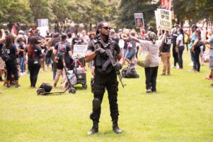 A protester standing at the rally holds a model weapon