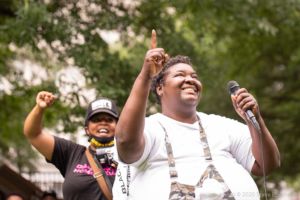 Protesters hold up their hands after giving speeches with a microphone