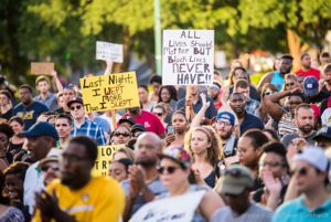 A crowd of protesters hold up signs as part of the protest