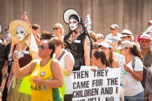 Protesters with faces painted with makeup march through the streets with other protesters