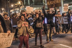Protesters march down Peachtree Street holding signs and using bullhorns to spread their message further