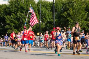 A runner goes by while carrying an American Flag on a pole with them