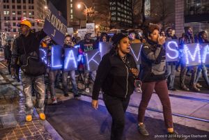 Protesters march down Peachtree Street carrying signs and speaking into a bullhorn