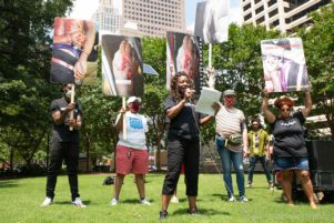 Monteria Robinson gives a speech to fellow protesters while standing in front of signs