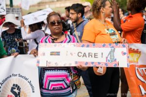 A protester holds up a sign reading 'I heart Care!'