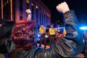 Protesters raise fists in the air as they stand in front of a police blockade