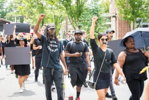 Protesters march through the streets with taped mouths and fists held in the air