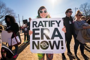 A woman holds up a 'Ratify ERA Now' sign
