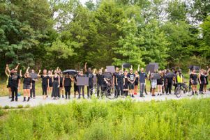 Protesters stand along the Beltline in a line with raised fists and signs