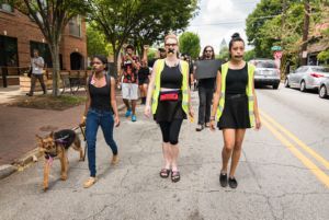 Protesters wearing construction safety vests march with tape over their mouths