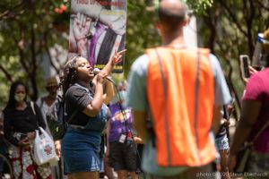 A protester holds her finger in the air while giving a speech