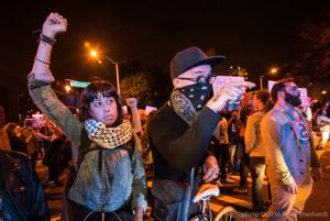 Protesters raise their fist in the air and point their fingers