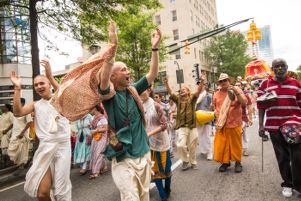 Dancers dance through the streets, clapping their hands