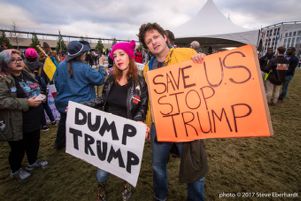 Protesters hold up signs reading 'Dump Trump' and 'Save U.S. Stop Trump'