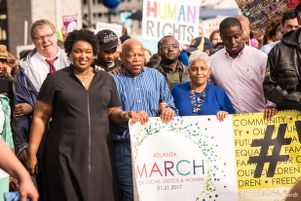 Representative John Lewis and Stacey Abrams march amonst other protesters carrying a banner