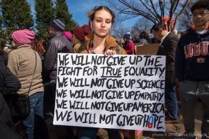 A protester holds a sign in the air saying that they will keep fighting for true equality