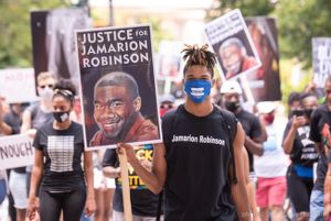 A protester holds up a sign reading 'Justice for Jamarion Robinson'
