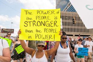 A female protester holds up a sign calling for the power of the people